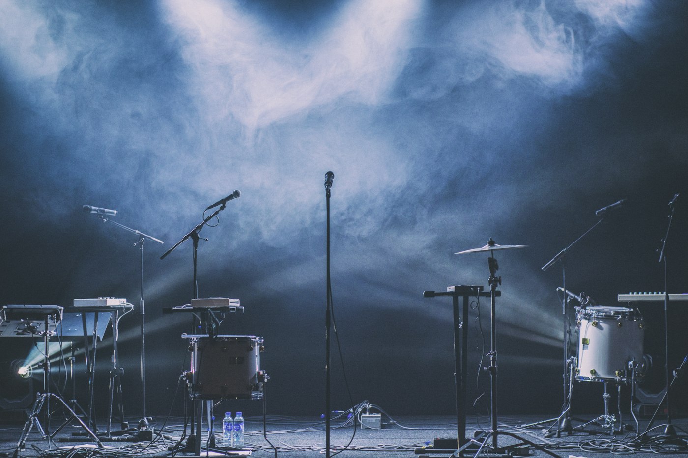 Instruments and microphones on a stage under blue lights